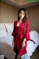 A woman in a red robe standing on a bed.