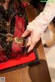 A woman's hand holding a red purse on a table.