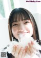 A young woman holding a fluffy white object in her hands.