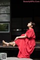 A woman in a red dress sitting on a bench.