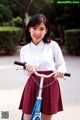 A young woman in a school uniform riding a bike.