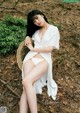 A woman in a white dress sitting on a wicker chair.