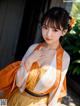 A woman in an orange and white kimono posing for a picture.