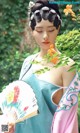 A woman in a blue and pink dress holding a fan.