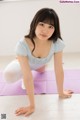 A young woman is doing yoga on a purple mat.