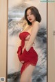 A woman in a red lingerie posing in front of a mirror.