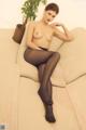 A woman in black pantyhose sitting on a white couch.